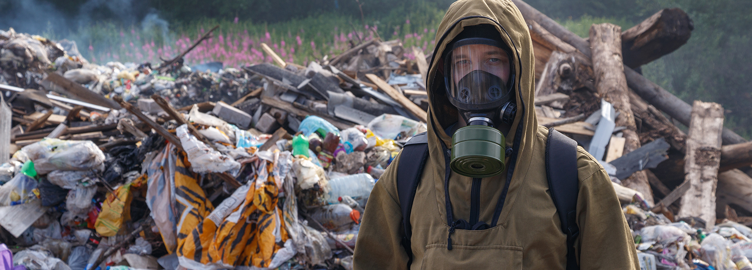 Een werkende man met gasmasker tegen de achtergrond van brandend afval.