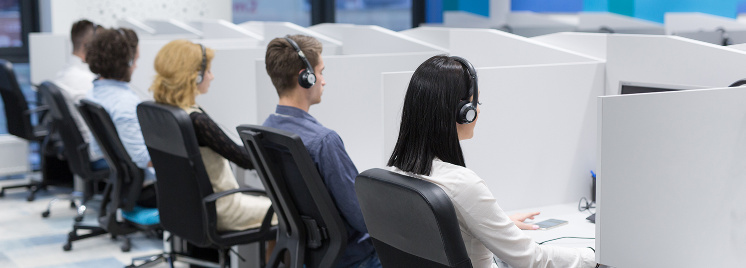 groep jonge mensen uit het bedrijfsleven met een headset in een call center geven ondersteuning aan klanten.