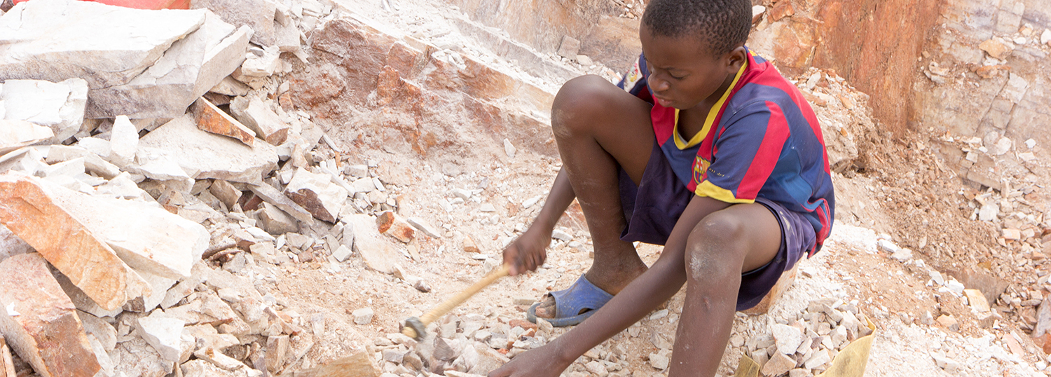Oegandees kind breekt stenen in kleine stukjes voor verkoop aan zijn overste.
